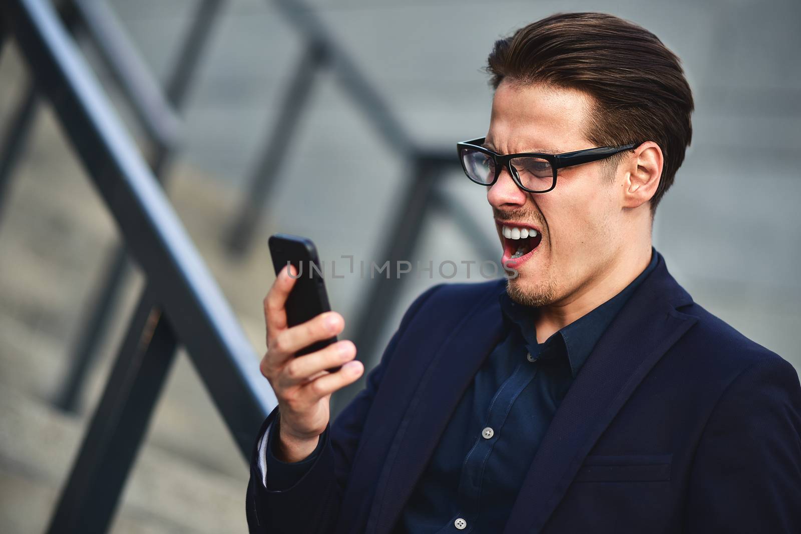 Angry caucasian businessman in glasses dressed at classic wear standing at the street.