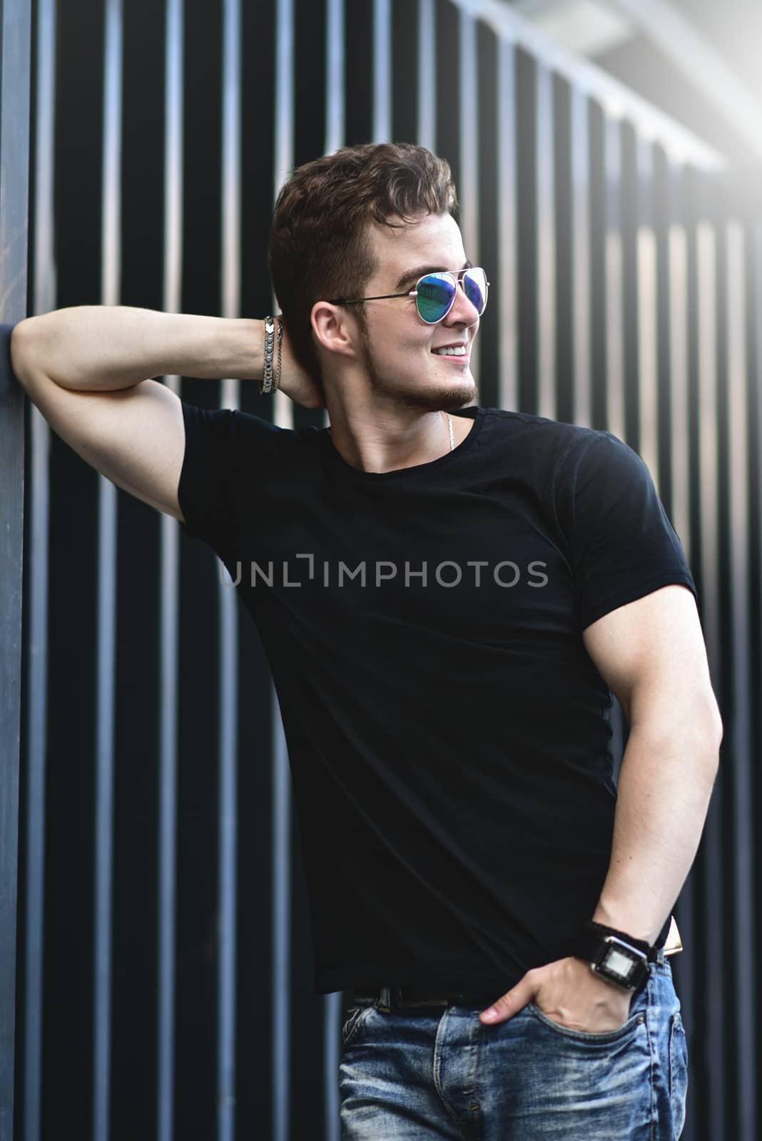 Young stylish and confident happy handsome guy model in t-shirt lifestyle in the street in sunglasses