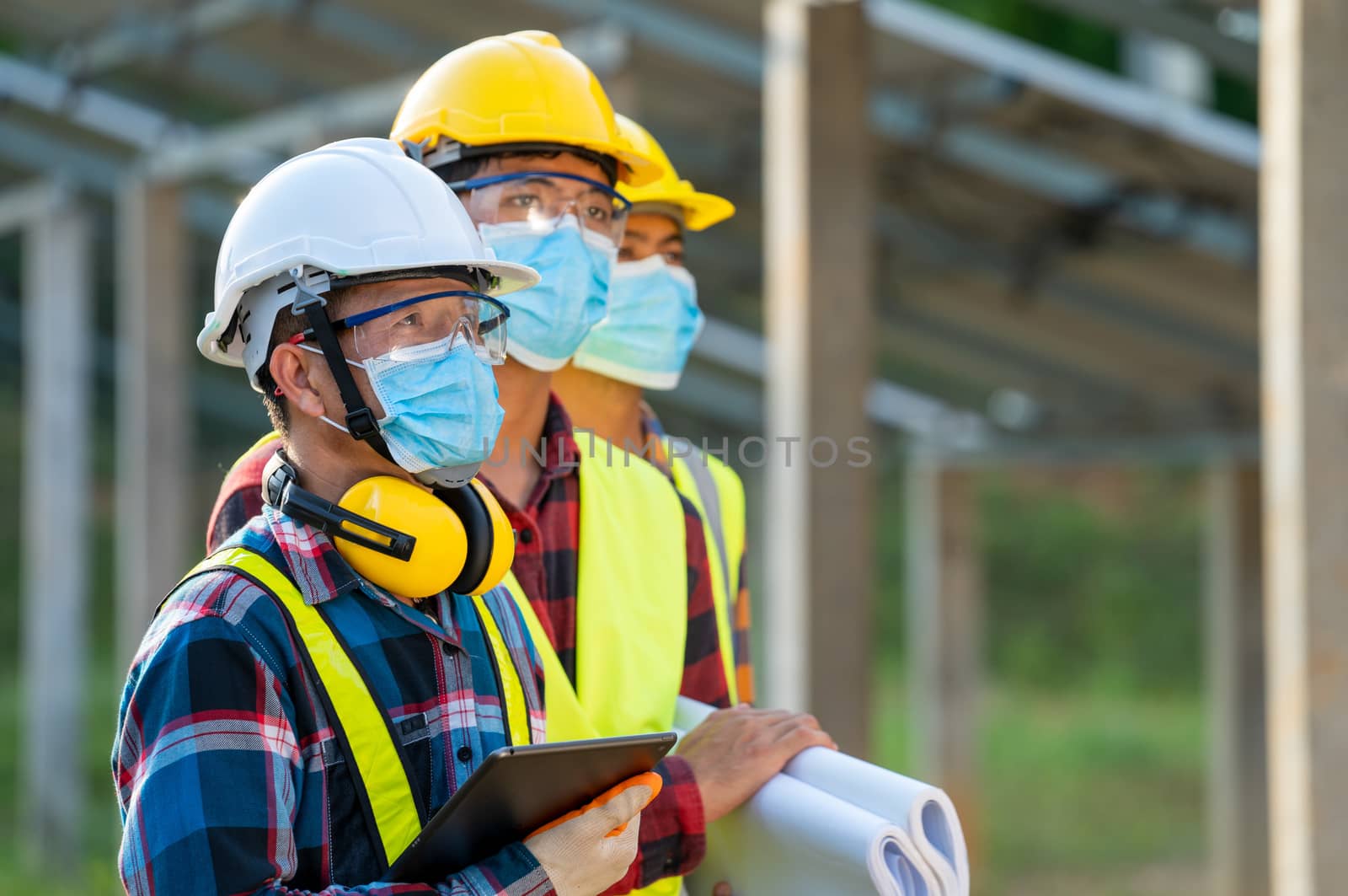 Engineer wearing protective mask to Protect Against Covid-19  working on checking and maintenance in solar power plant,Solar power plant,Science solar energy.
