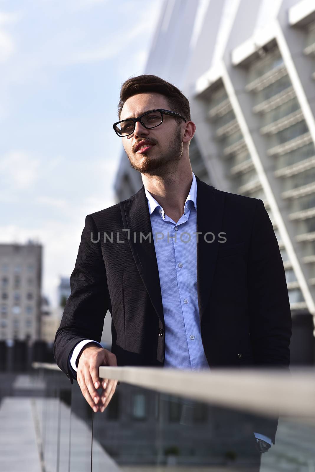 Modern businessman. Confident young man in full suit standing outdoors with cityscape in the background
