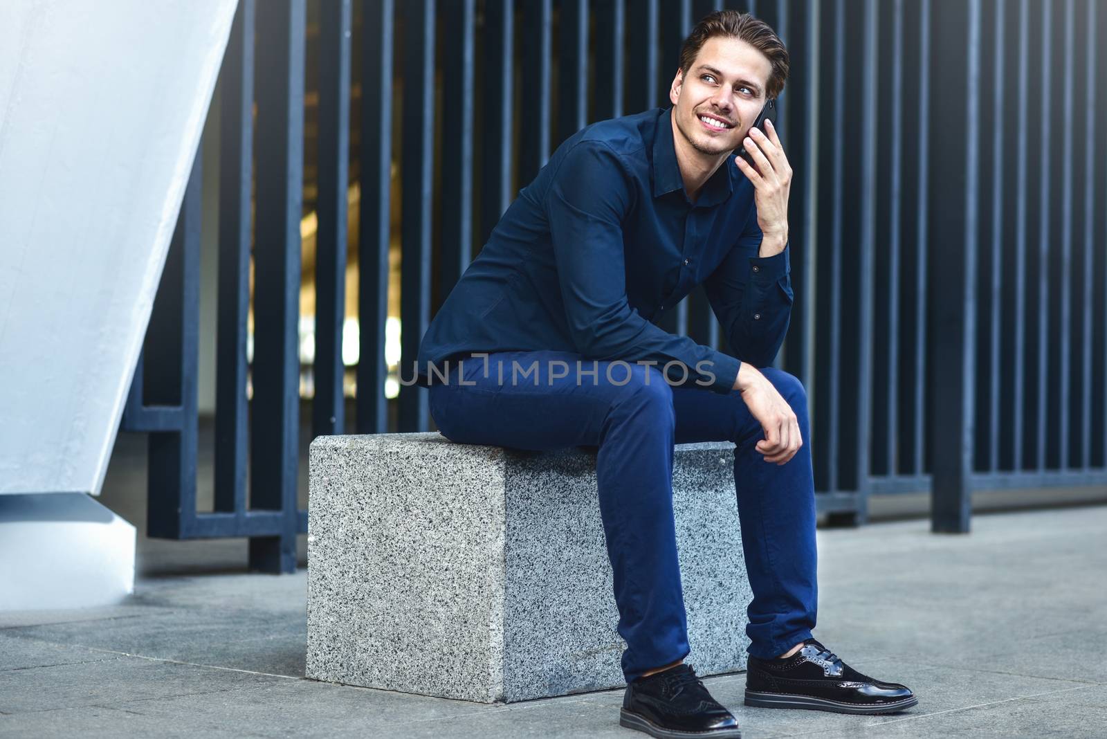 Successful caucasian businessman with smartphone at street in the city.