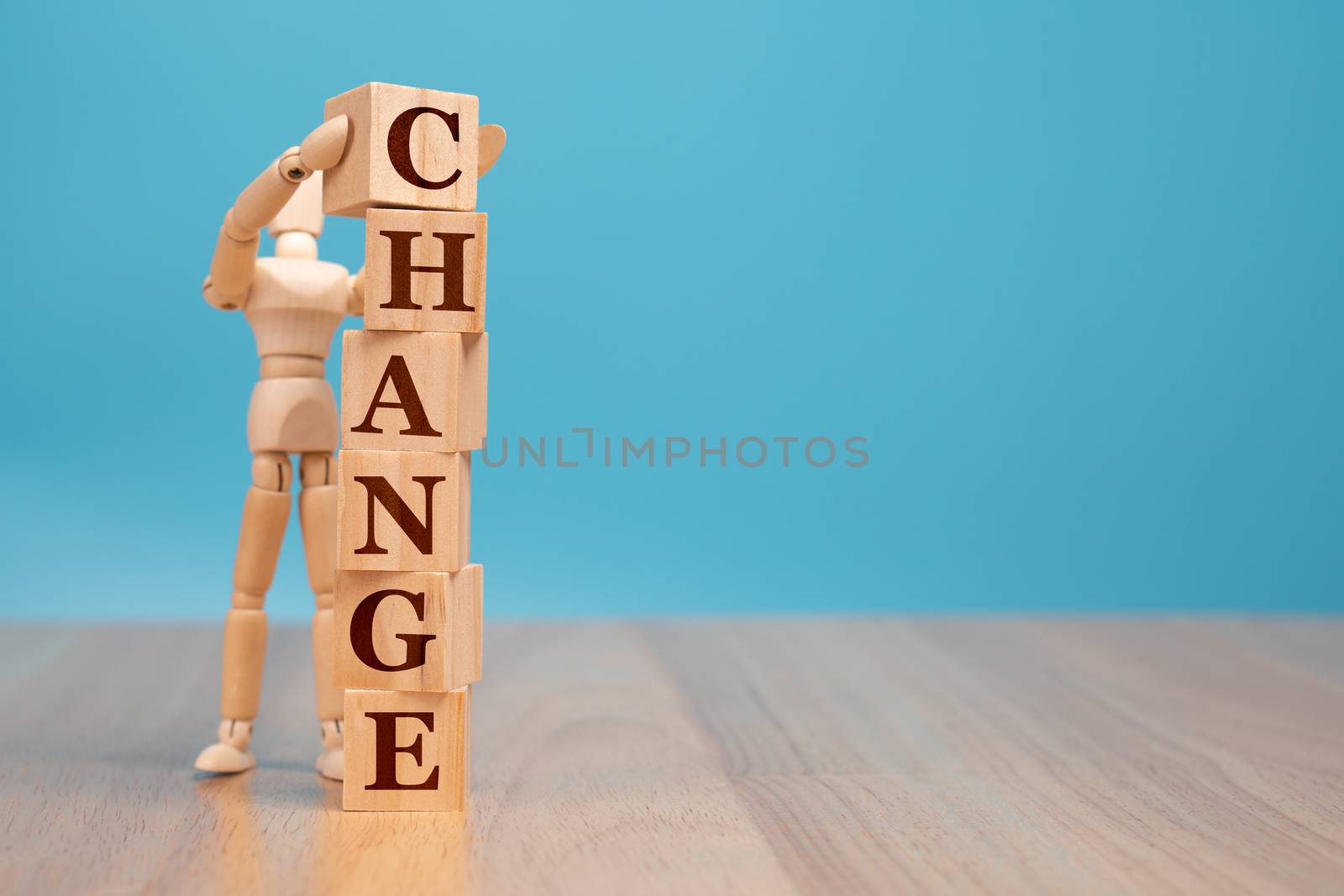 Wooden puppet standing and holding a wooden cube with word change to chance, Concept of self development for career, business success, and leadership by PattyPhoto
