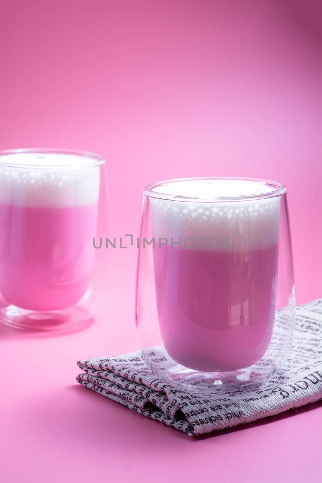 Summer drink concept. Strawberry pink milk with froth milk in clear glass on pink background. 