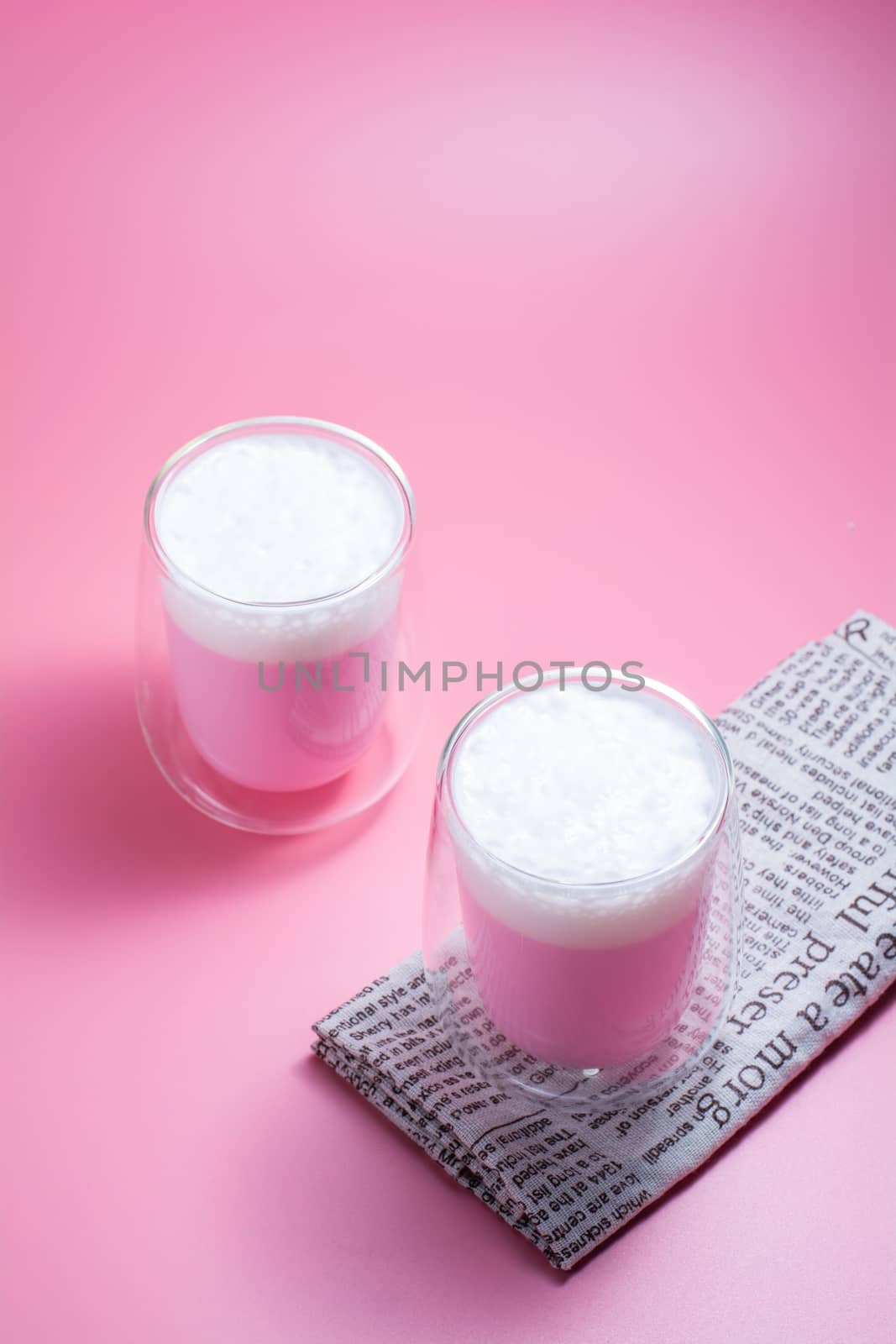 Summer drink concept. Strawberry pink milk with froth milk in clear glass on pink background. 