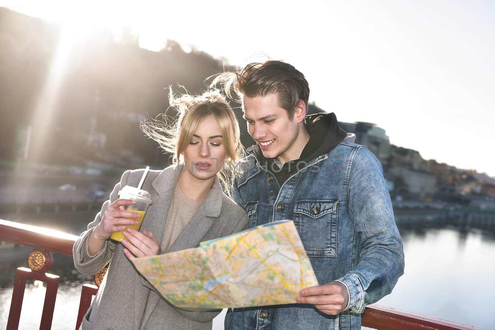 A beautiful young tourist couple are standing on the bridge and looking around