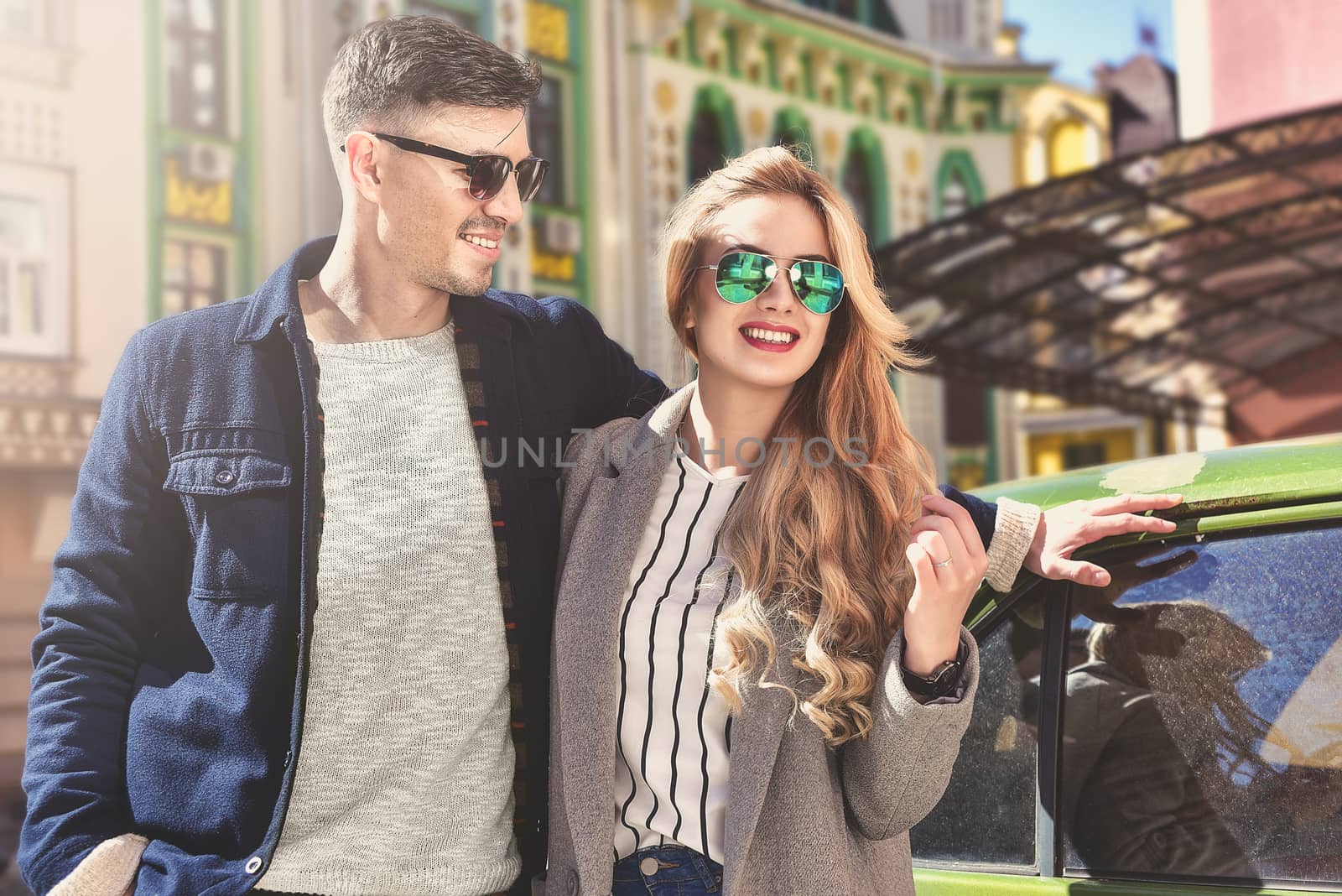 Couple enjoy the sunny mood standing near the car