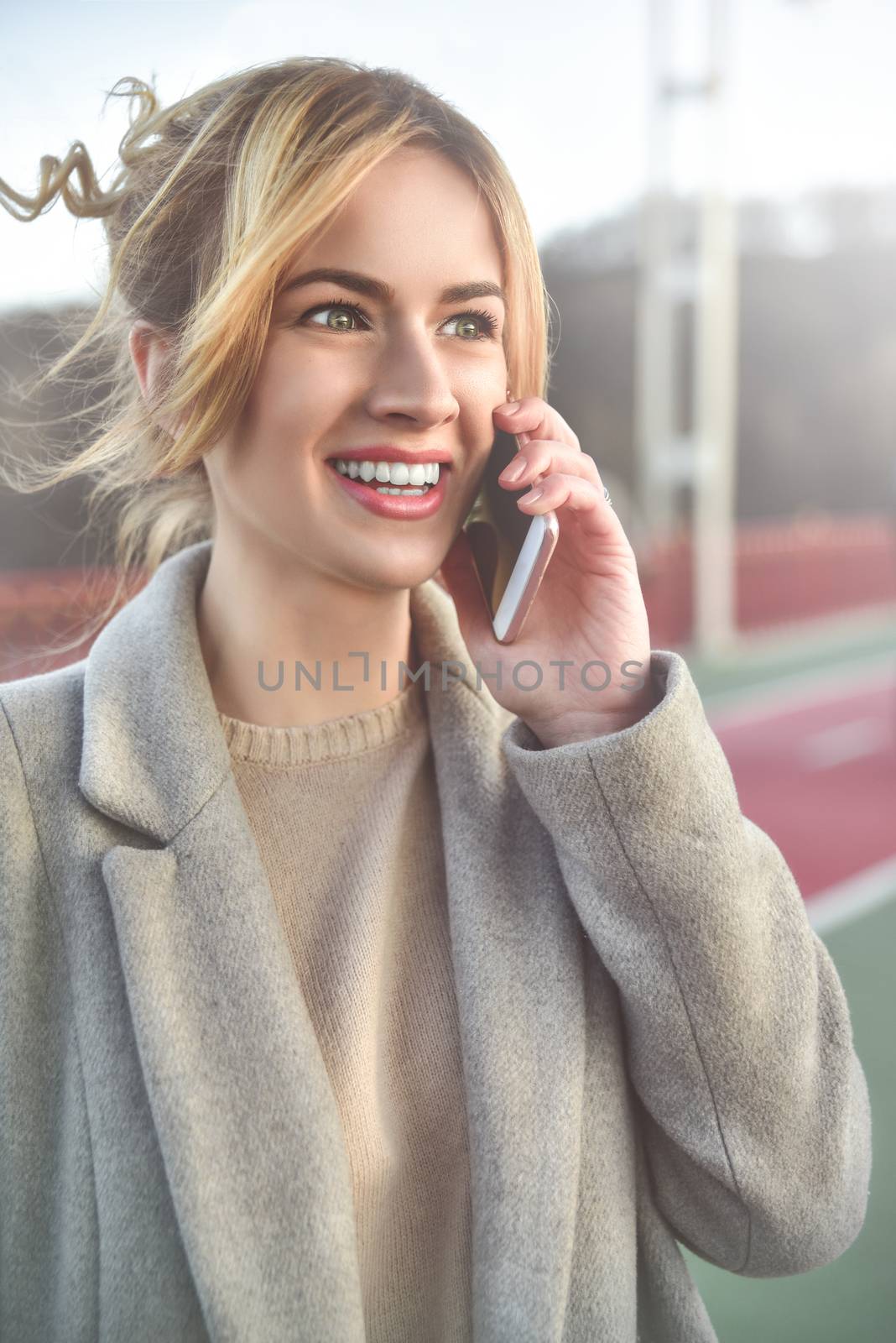 Cute smiling young woman talking on phone standing on the bride. Close up portrait