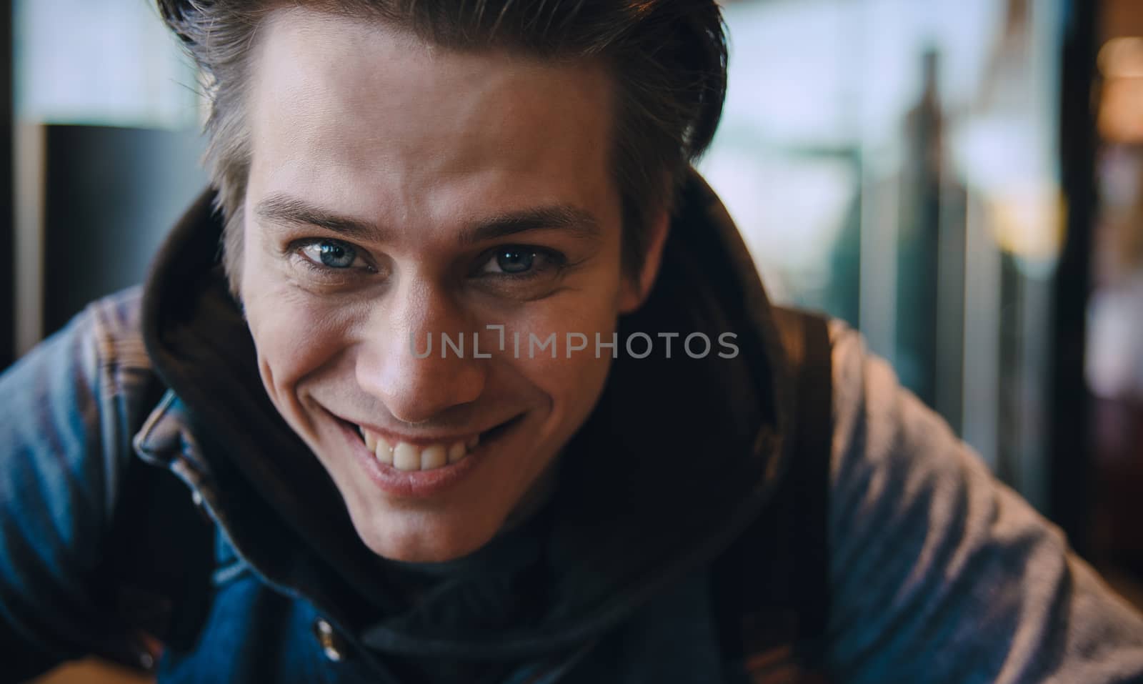 Close up photo of handsome Caucasian man looking and smiling at camera with happy cheerful expression.