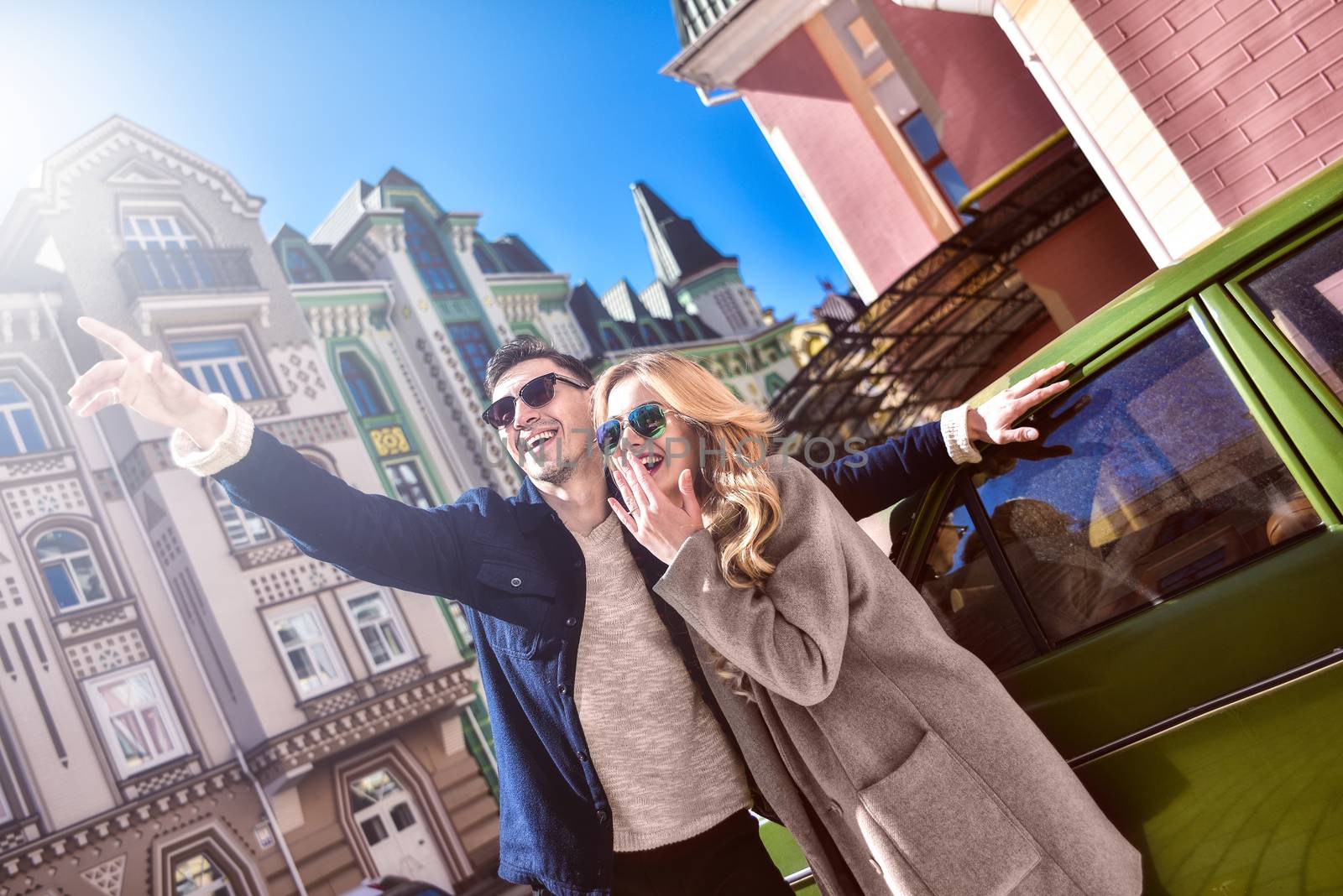 Couple in sunglasses standing near the car and looking for new apartment