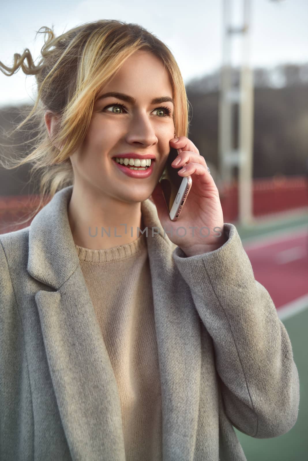 Cute smiling young woman talking on phone standing on the bride. Close up portrait