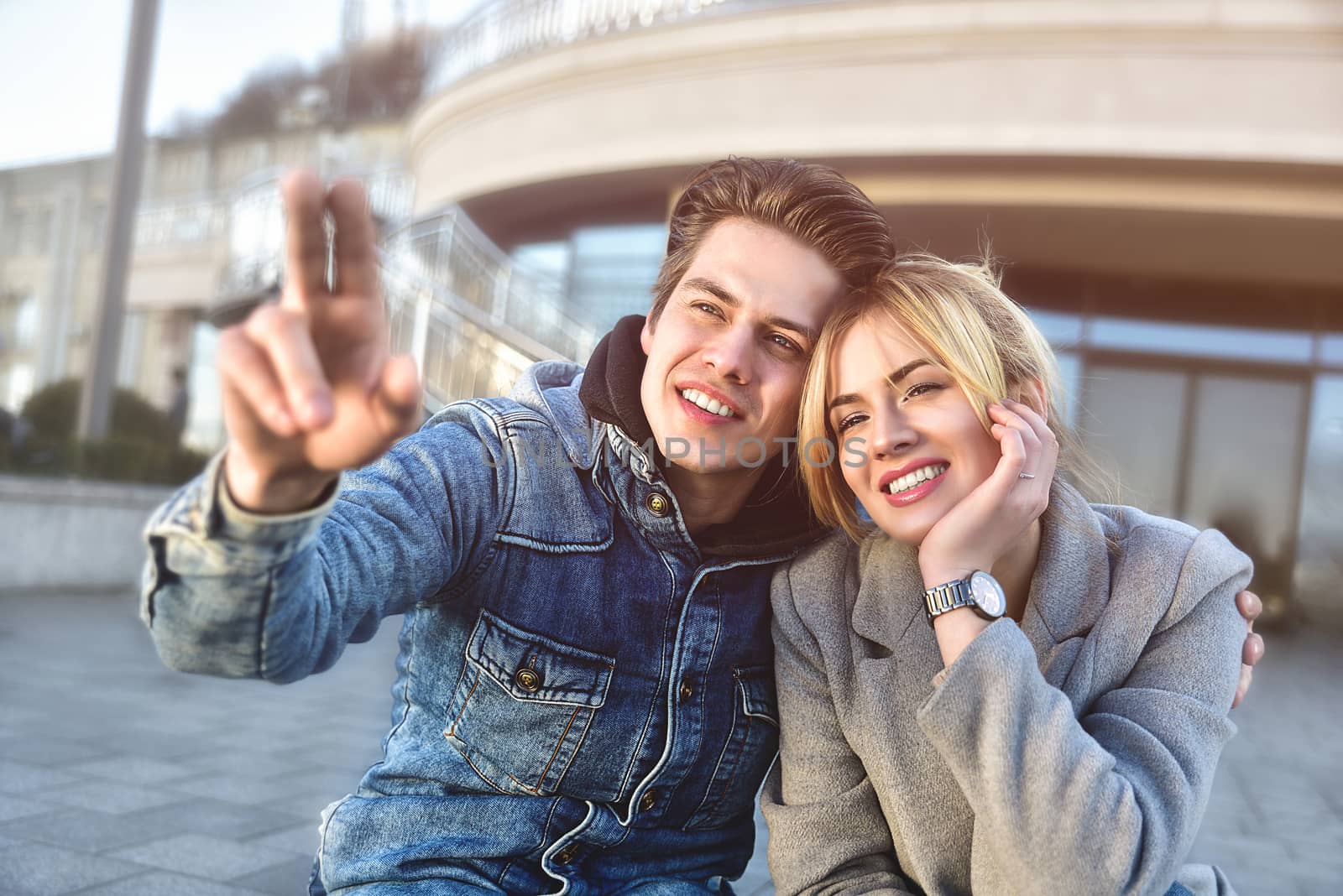 Attractive young couple sitting on floor in urban street and dreaming about something.