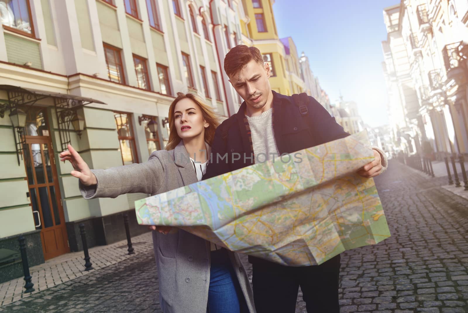 Couple of young tourists reading a map in the city