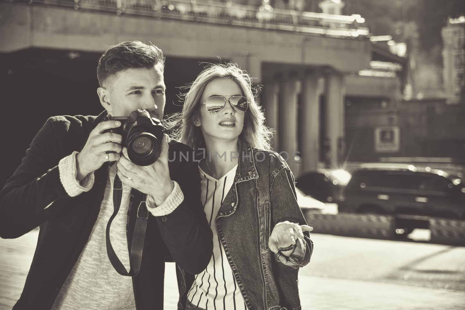 Romantic couple walk at the street with photo camera in BW