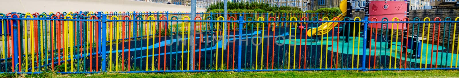 Panorama of a Colorful garden fence with playground int the background by paddythegolfer
