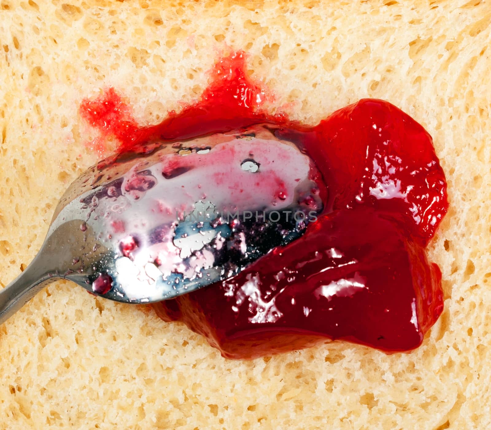 red strawberry marmalade preserves, spread over a slice of white bread