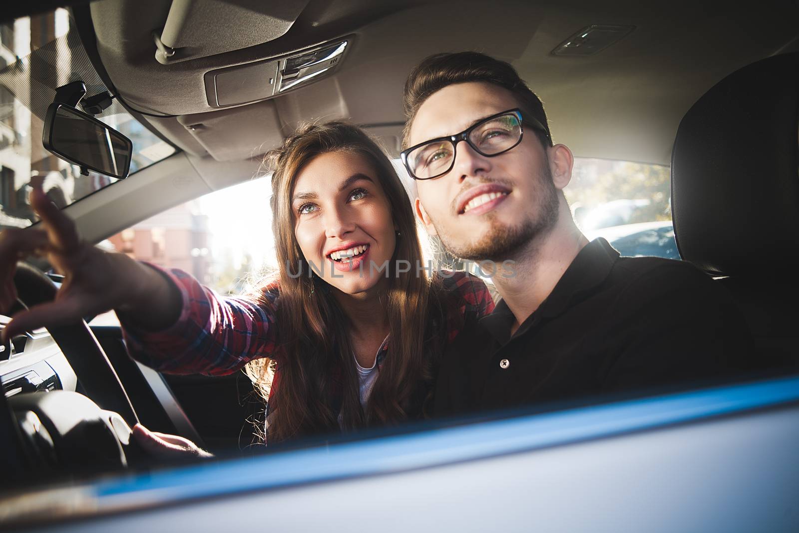 Young caucasian couple in car having fun on road trip by Nickstock