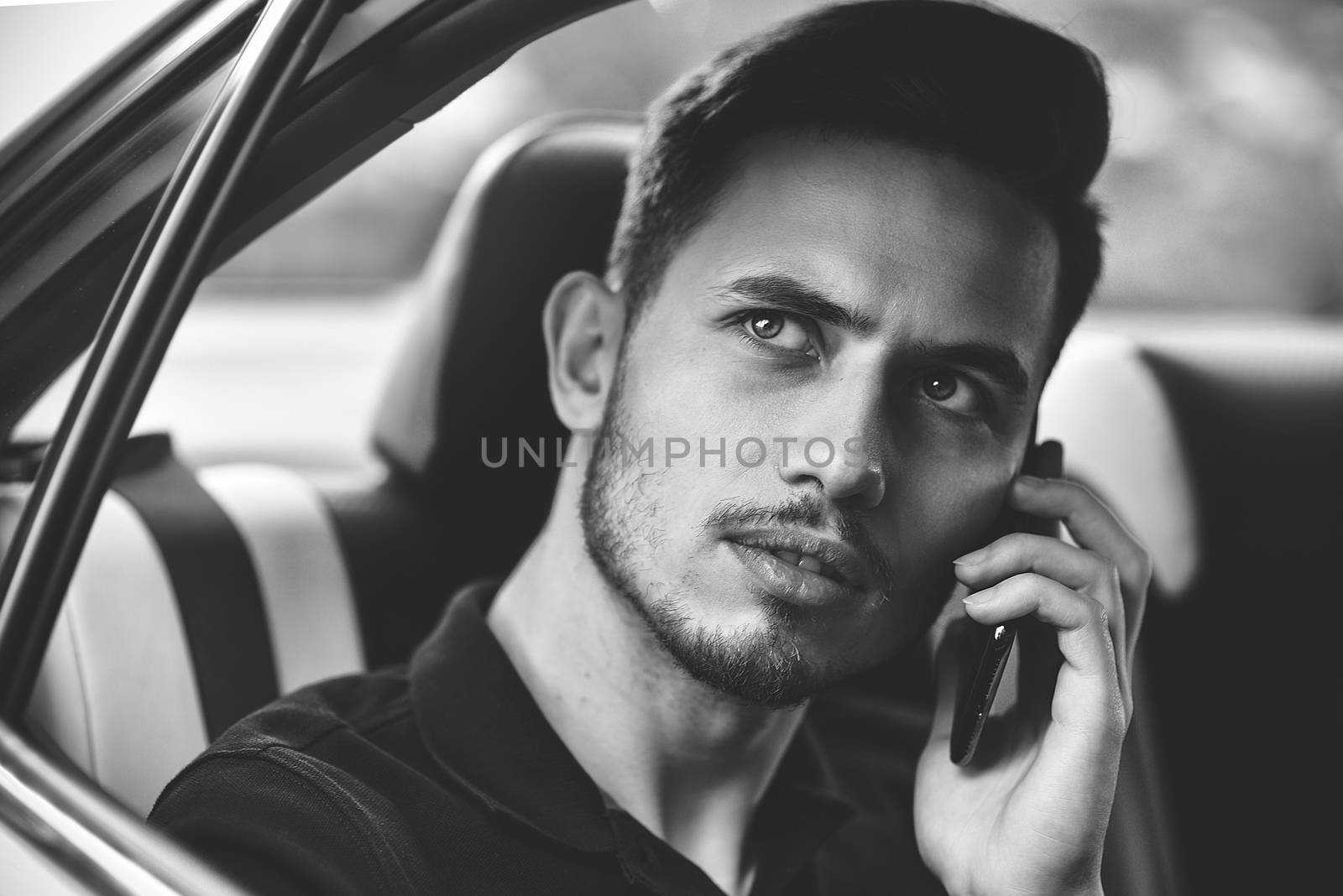 Handsome man sit in the back seat of the car and use a phone.
