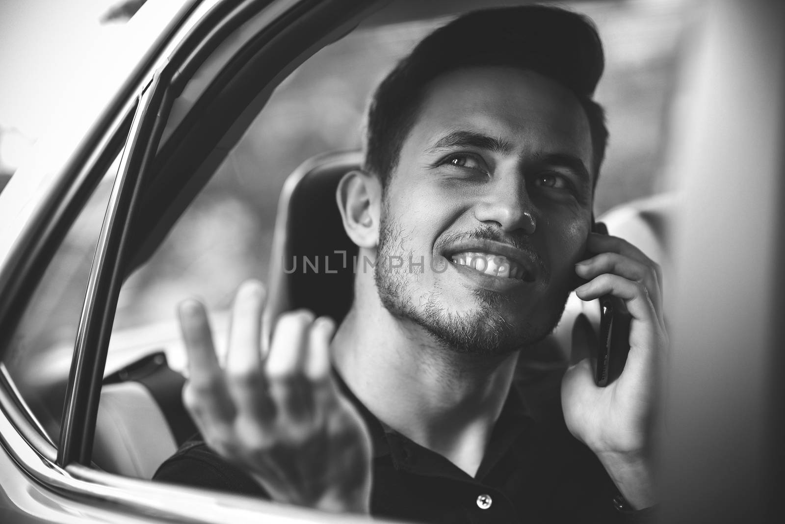 Handsome man sit in the back seat of the car and use a phone.