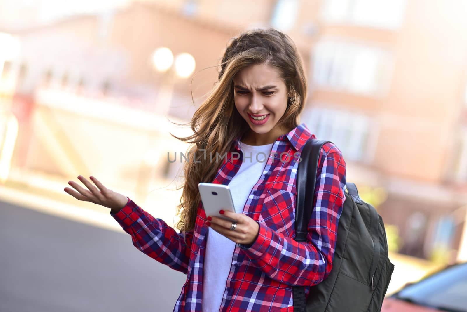 Young girl talking on the phone in the street surfing on the phone