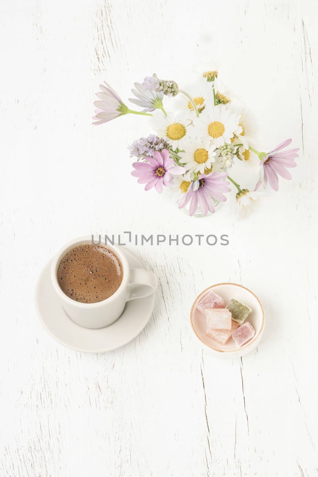 Cup of coffee and Turkish delight on a wooden table with colorful spring flowers on