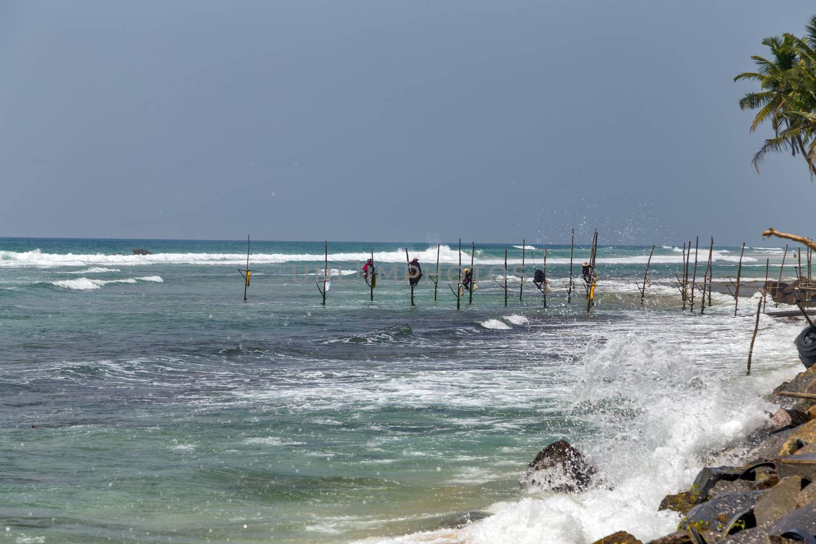 Local traditional stilt fishermen fishing rod in Indian ocean, Sri Lanka.
