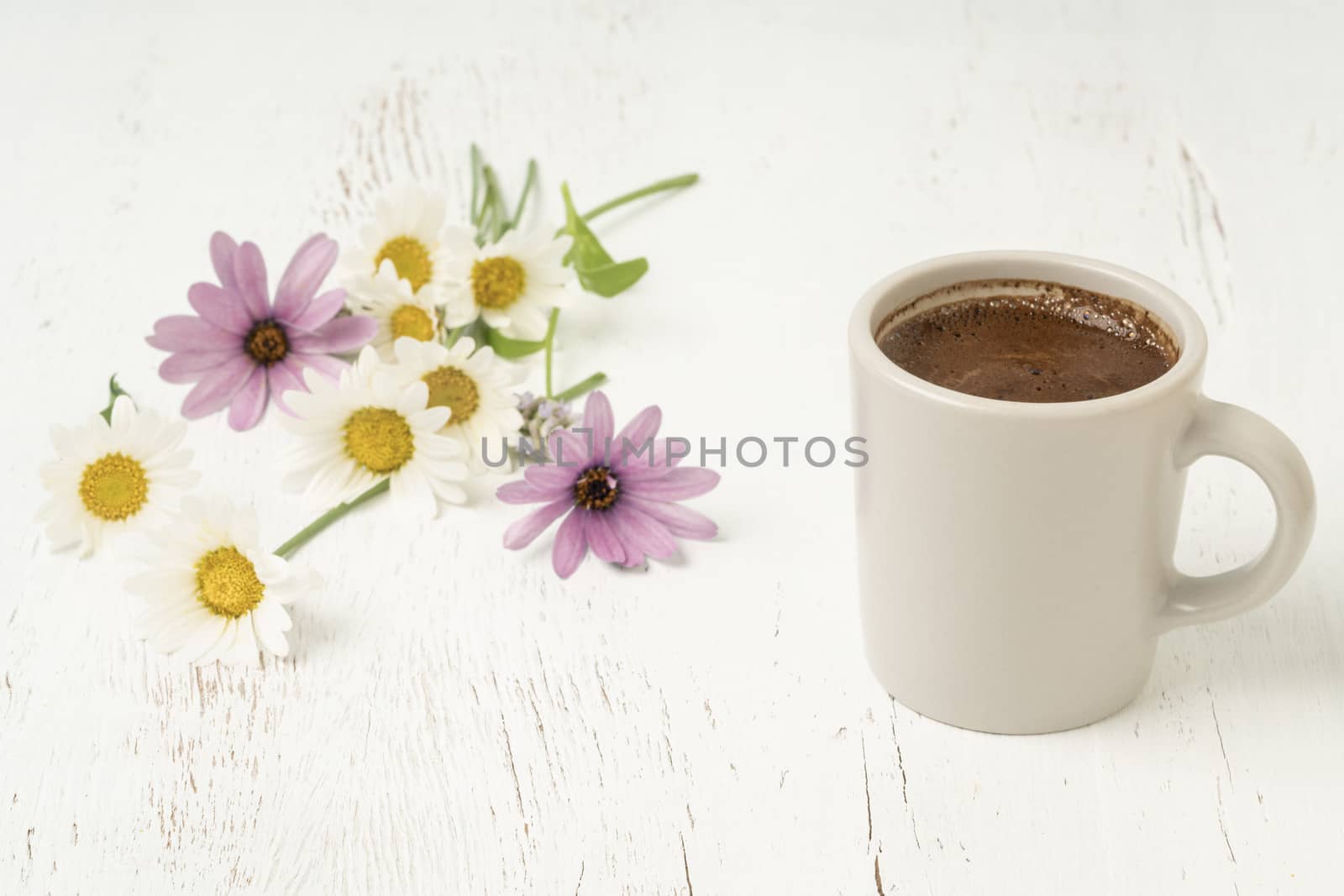 A cup of coffee on a wooden table decorated with spring flowers