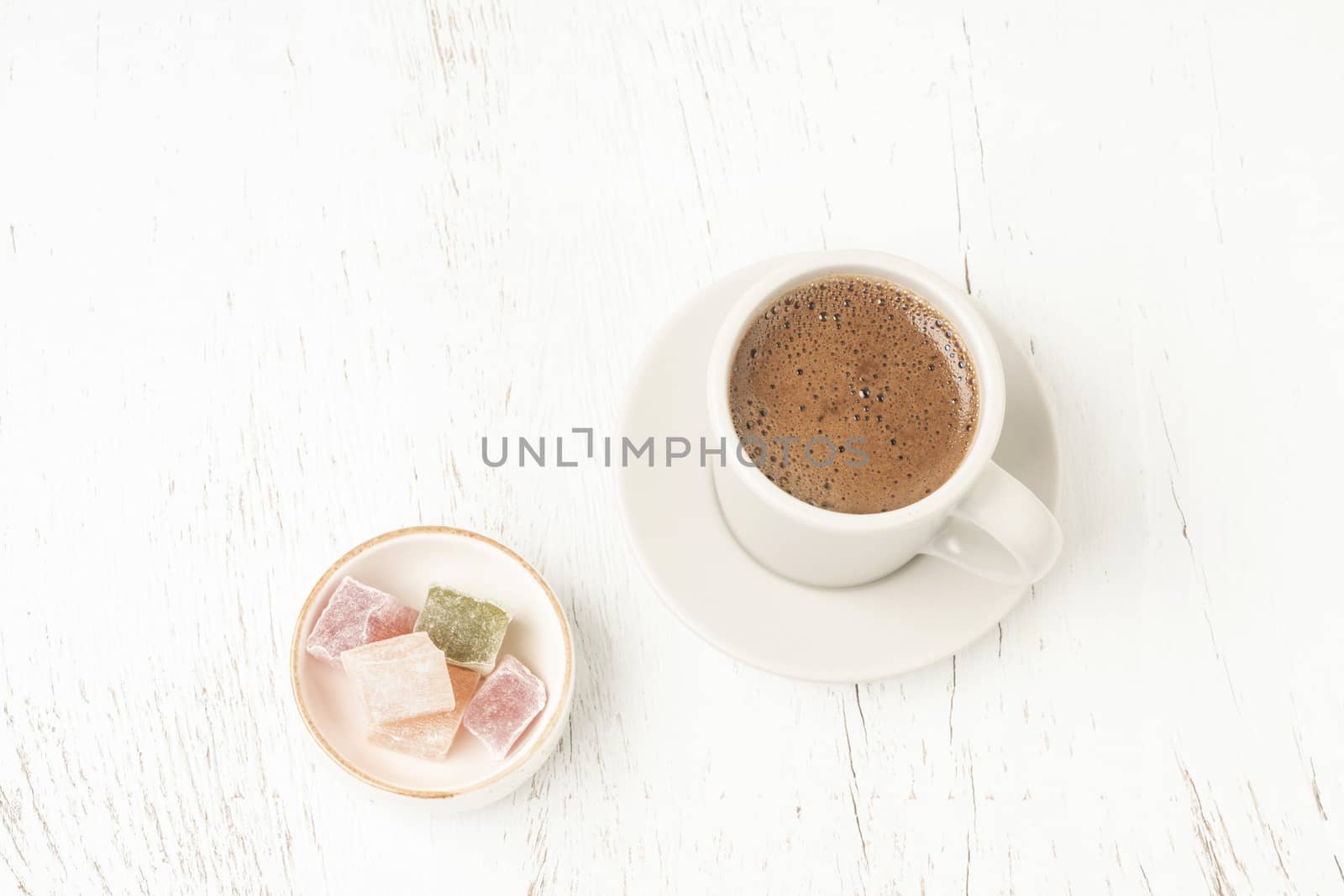Cup of coffee and colorful Turkish delights on a wooden table with copy space