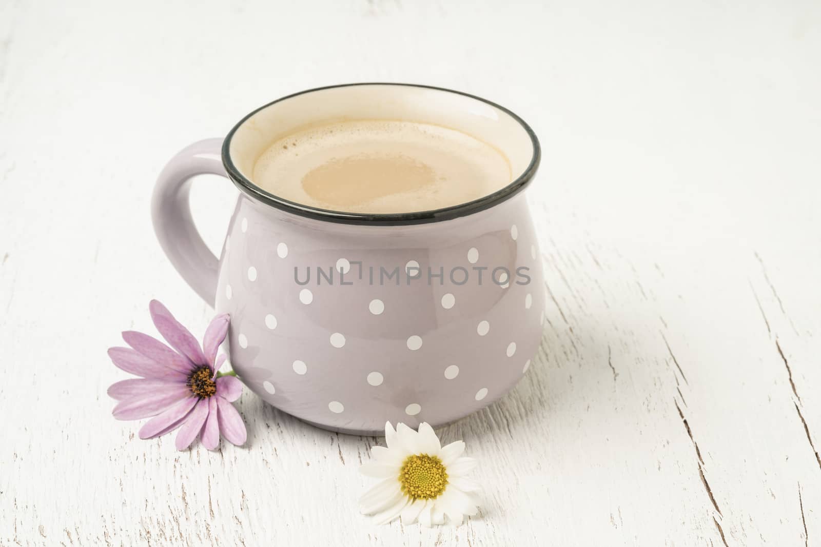 a cup of cappuccino or coffee latte on a wooden table decorated with spring flowers