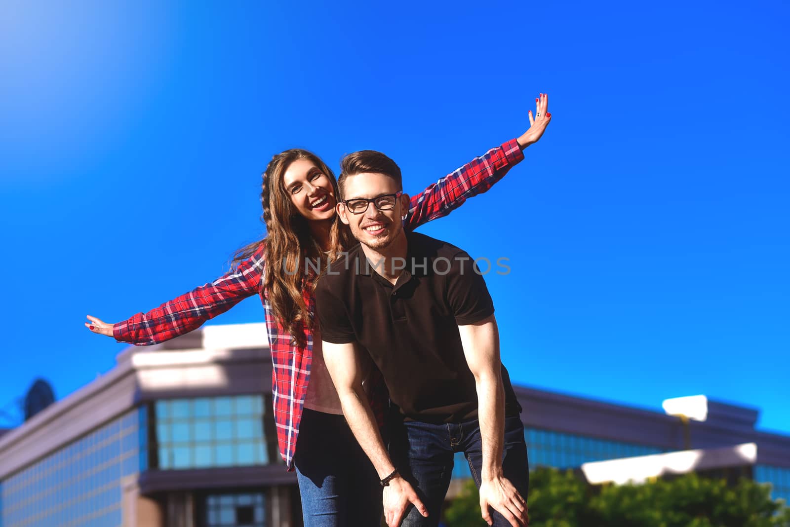 Outdoor shot of man giving woman piggyback. Man carrying woman oh his back