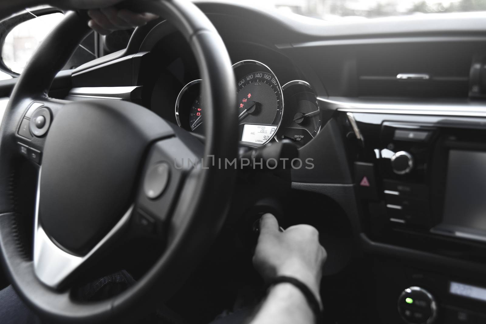 Male arms holding leathern rudder of car