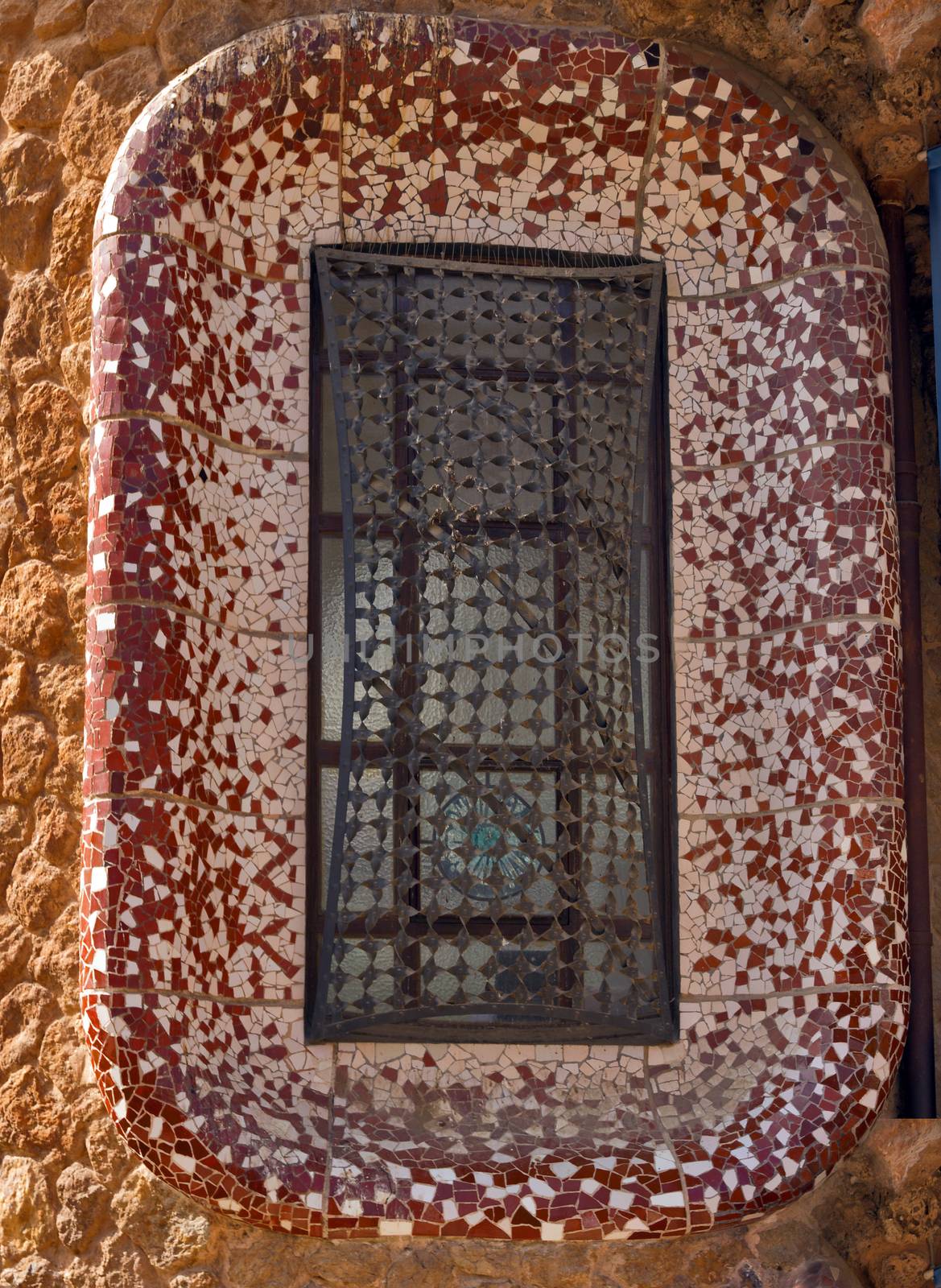 window ceramic tile grunge background covered with tile-shard mosaic, Parc Guell designed by Antoni Gaudi located on Carmel Hill, Barcelona, Spain.