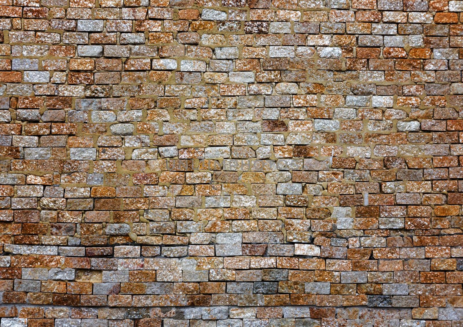 facade texture of stained old brick wall background, grungy rusty blocks of stone-work colorful horizontal architecture