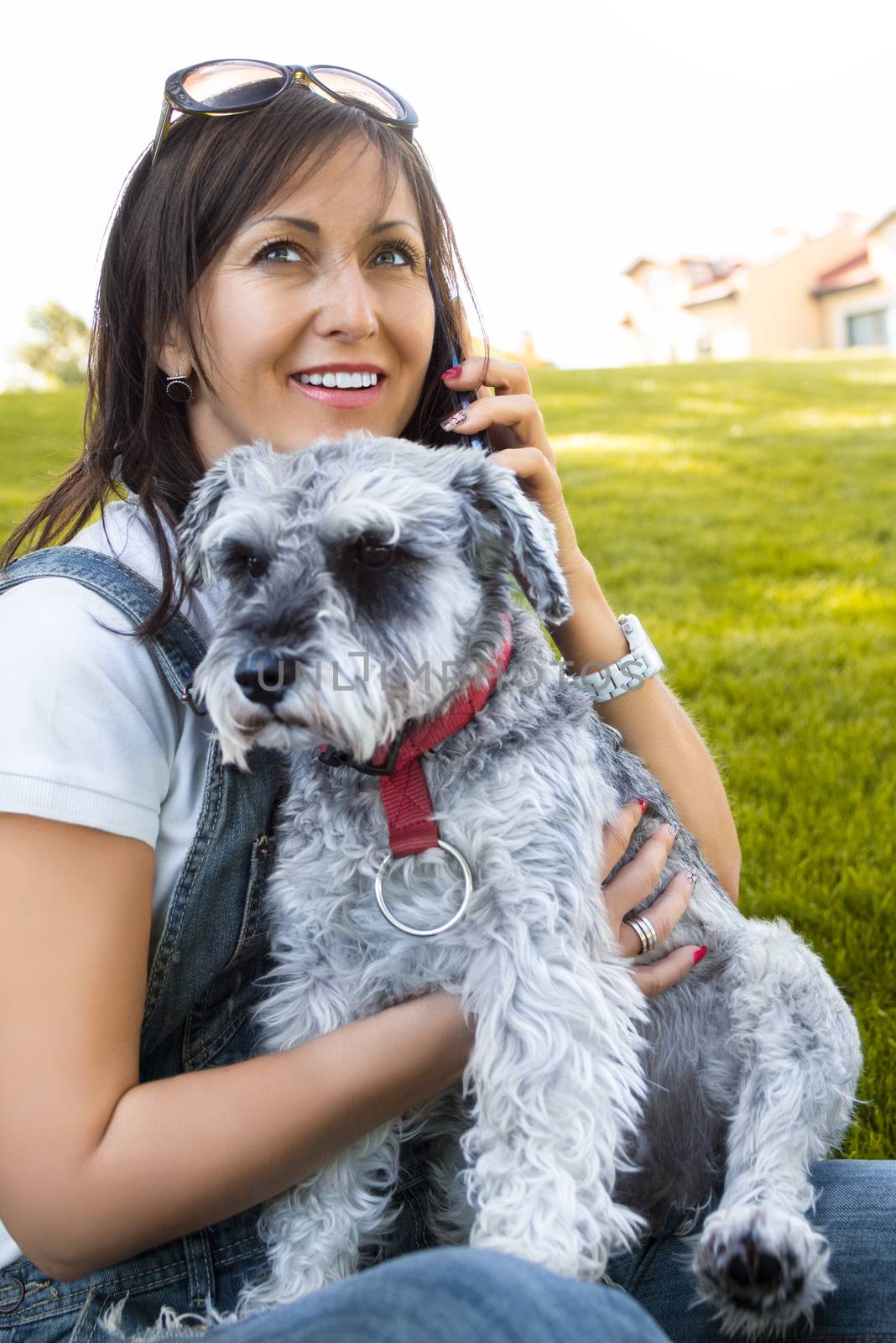 Portrait of a happy caucasian woman who hugs her beloved schnauzer dog and talking by the phone.The concept of love for animals. best friends by Nickstock