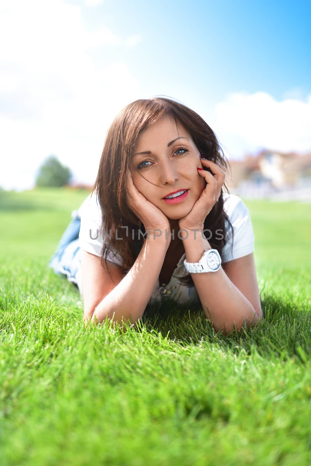 summer-vacation, adult woman relaxed lying on green grass in an outdoor park. girl in sunglasses enjoying nature lying on grass