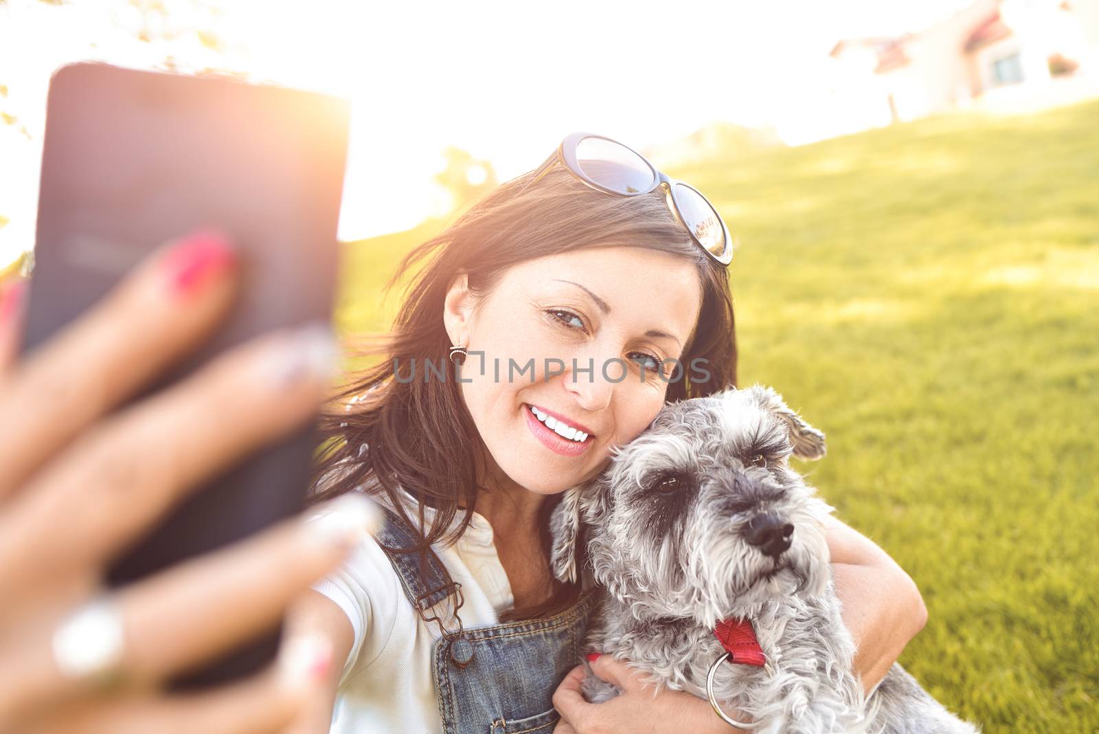 Portrait of a happy caucasian woman who hugs her beloved dog and Makes selfie with him .The concept of love for animals. best friends. Dog breed Schnauzer. sunny day by Nickstock