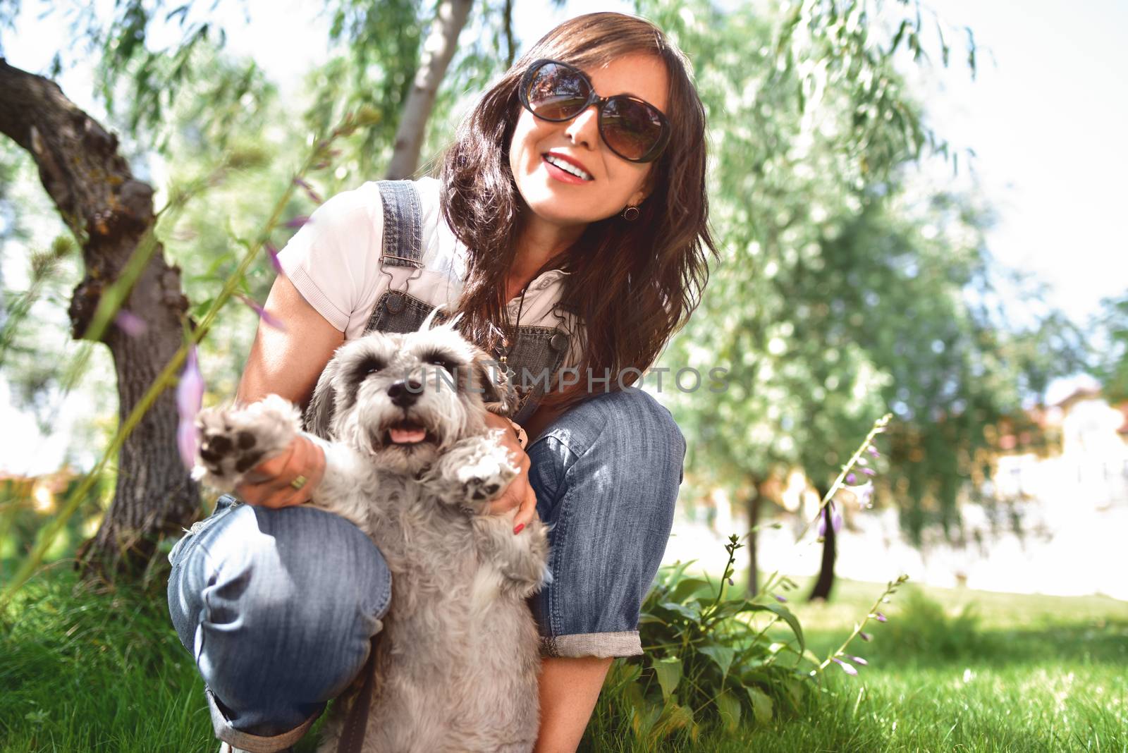 happy caucasian woman in sunglasses resting in nature with her beloved dog schnauzer.