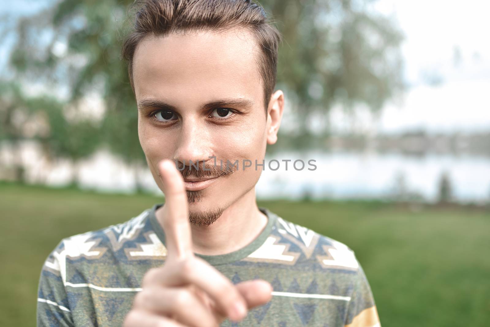 a guy with a sly expression on his face, shows a finger gesture, do not try to deceive me