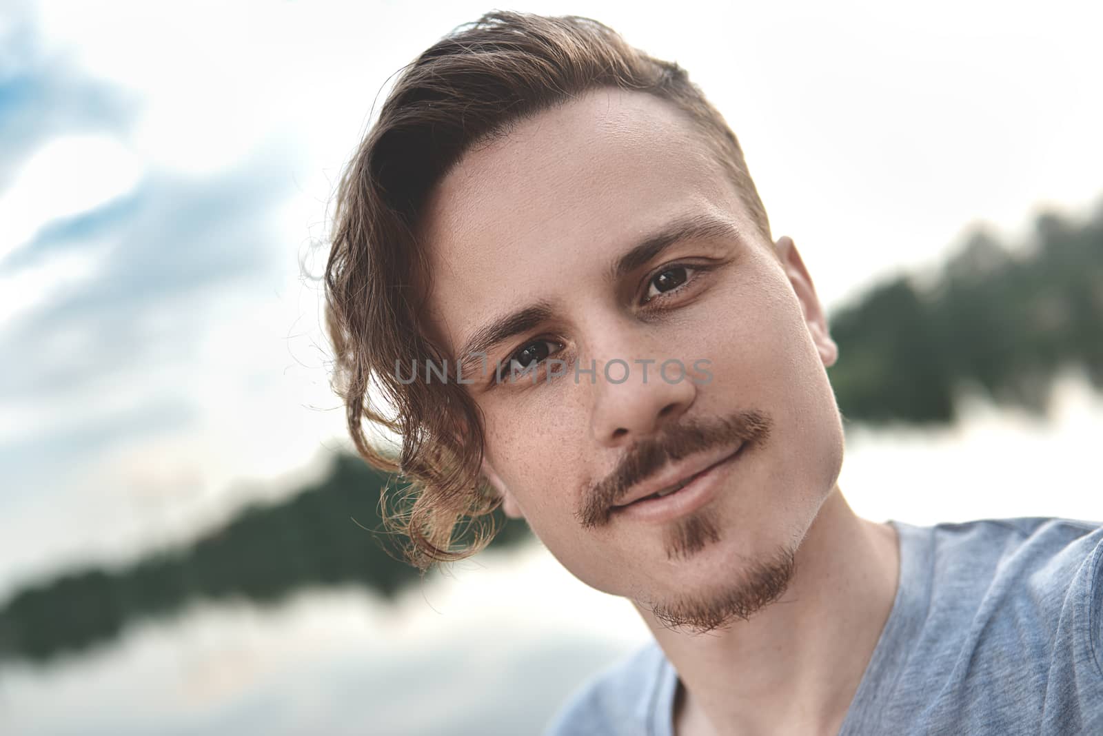 Handsome caucasian guy takes a selfie at the beach - people, lifestyle and technology concept