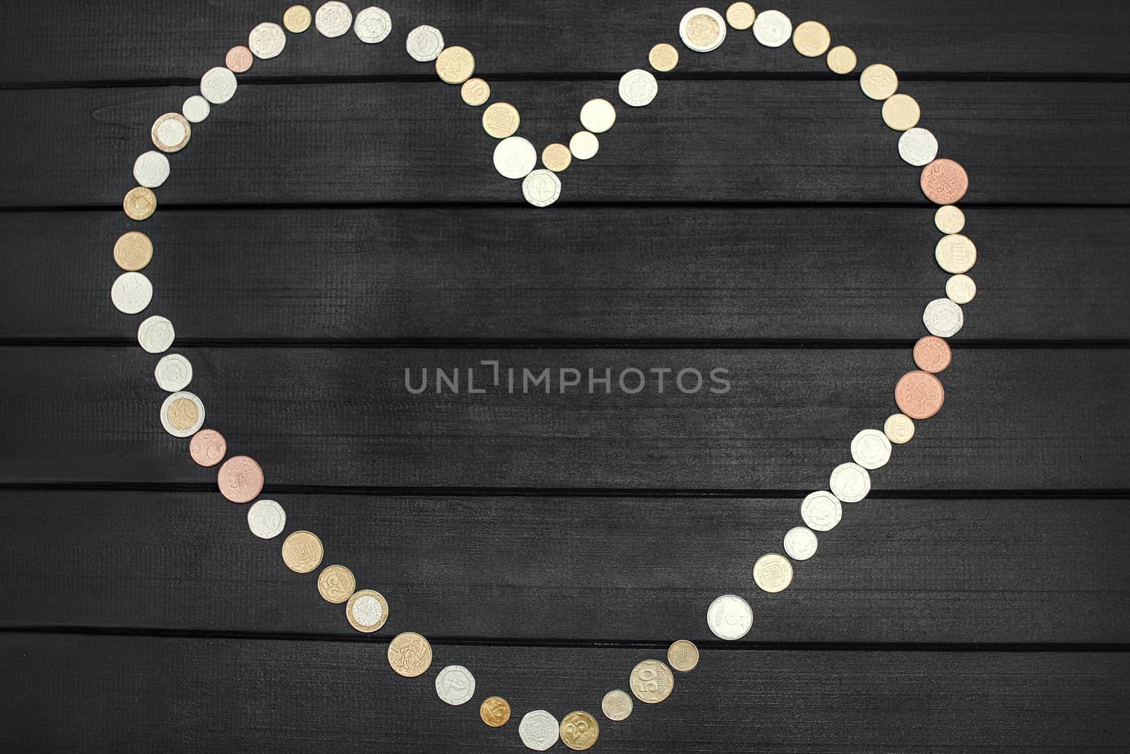 Scattered coins of different countries in the form of a question mark and an exclamation point on wooden table.
