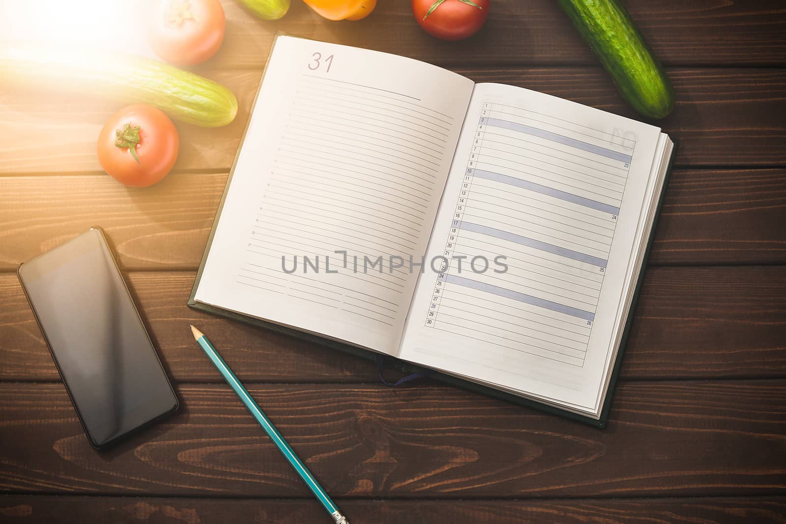 Dieting concept with a smartphone and a notepad and pen surrounded by lots of healthy fruit and vegetables.