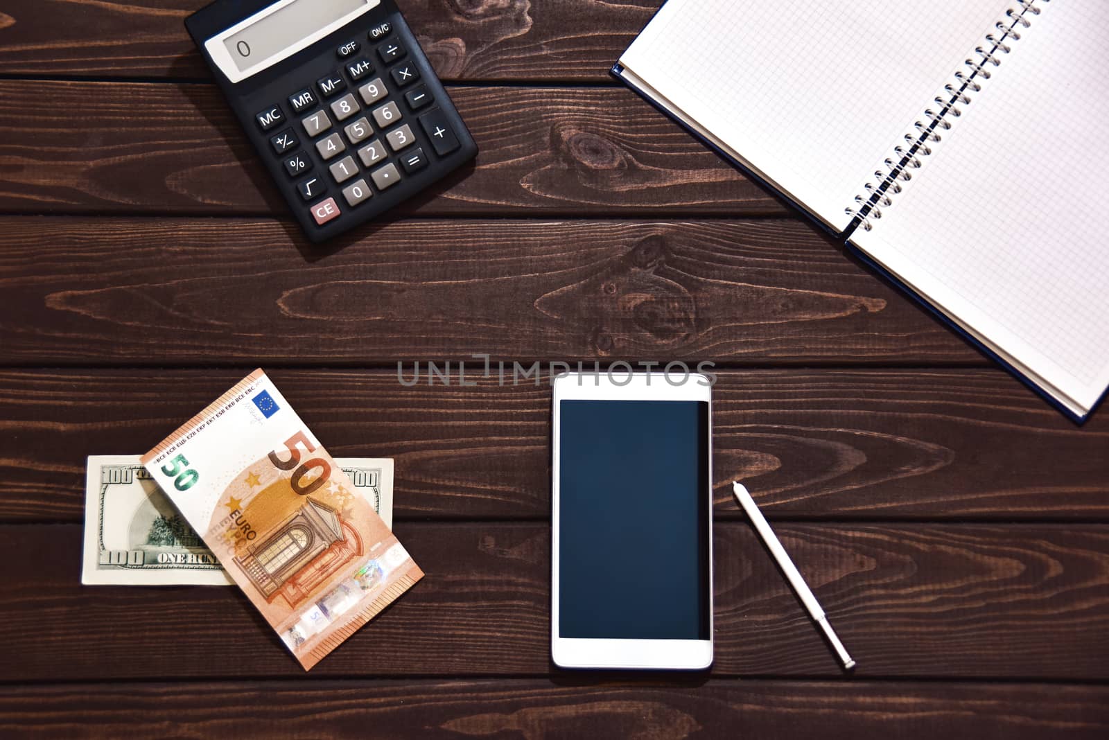 Top view of tablet, smartphone, calculator, notepad on white background, planning personal income, financial concept. Hand is typing on the calculator for money plan.