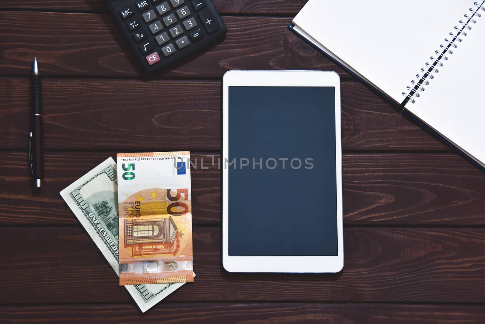 Top view of tablet, smartphone, calculator, notepad on white background, planning personal income, financial concept. Hand is typing on the calculator for money plan.