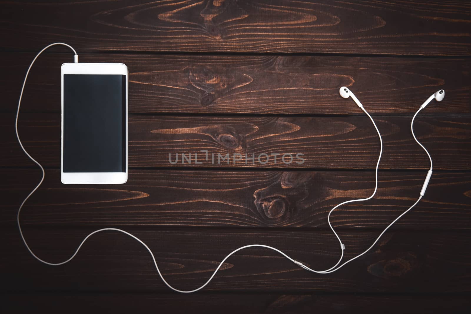 white smartphone with white headphones on wooden background- Image.Listening to music