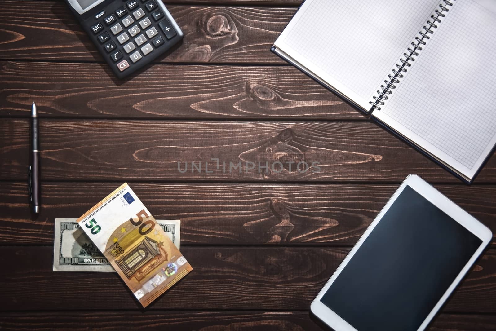 Top view of tablet, smartphone, calculator, notepad on white background, planning personal income, financial concept. Hand is typing on the calculator for money plan.