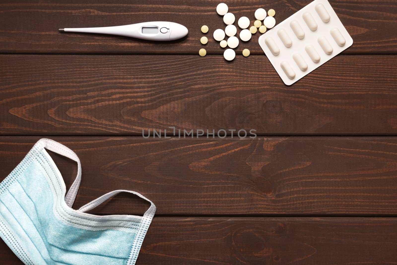 medical protective mask with medicines, thermometer on a wooden background, copy space
