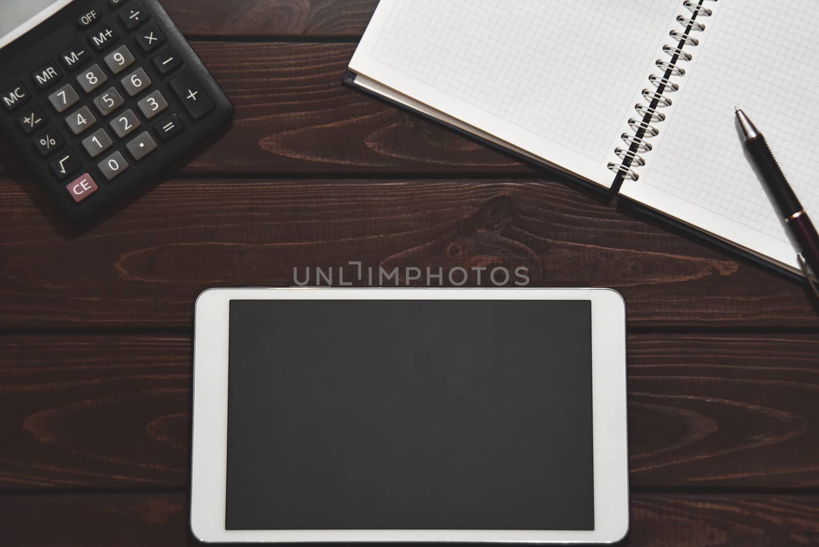 Top view of tablet, smartphone, calculator, notepad on wooden background, planning personal income, financial concept. typing on the calculator for money plan.