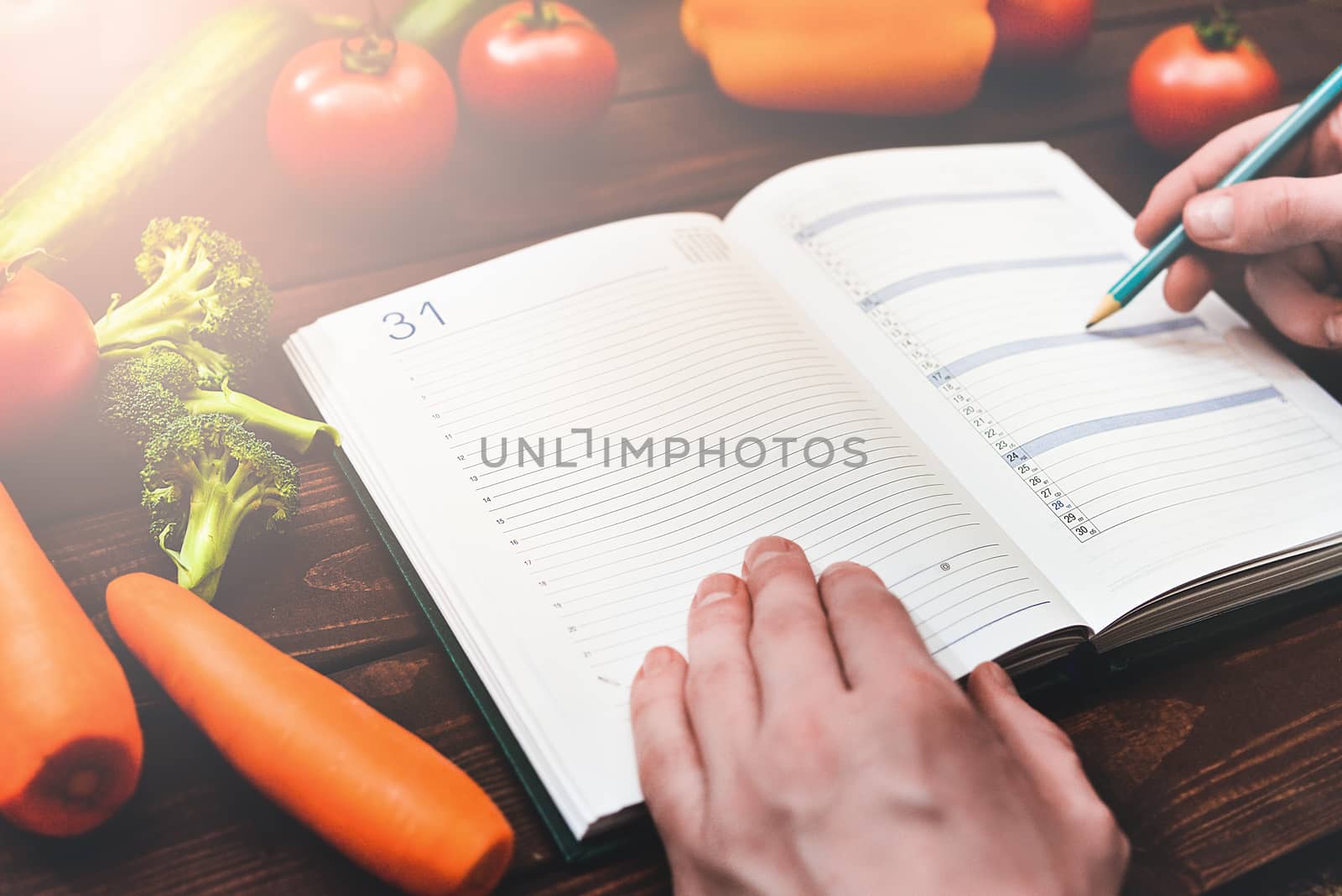 Dieting concept with a notepad and pen surrounded by lots of healthy fresh vegetables.