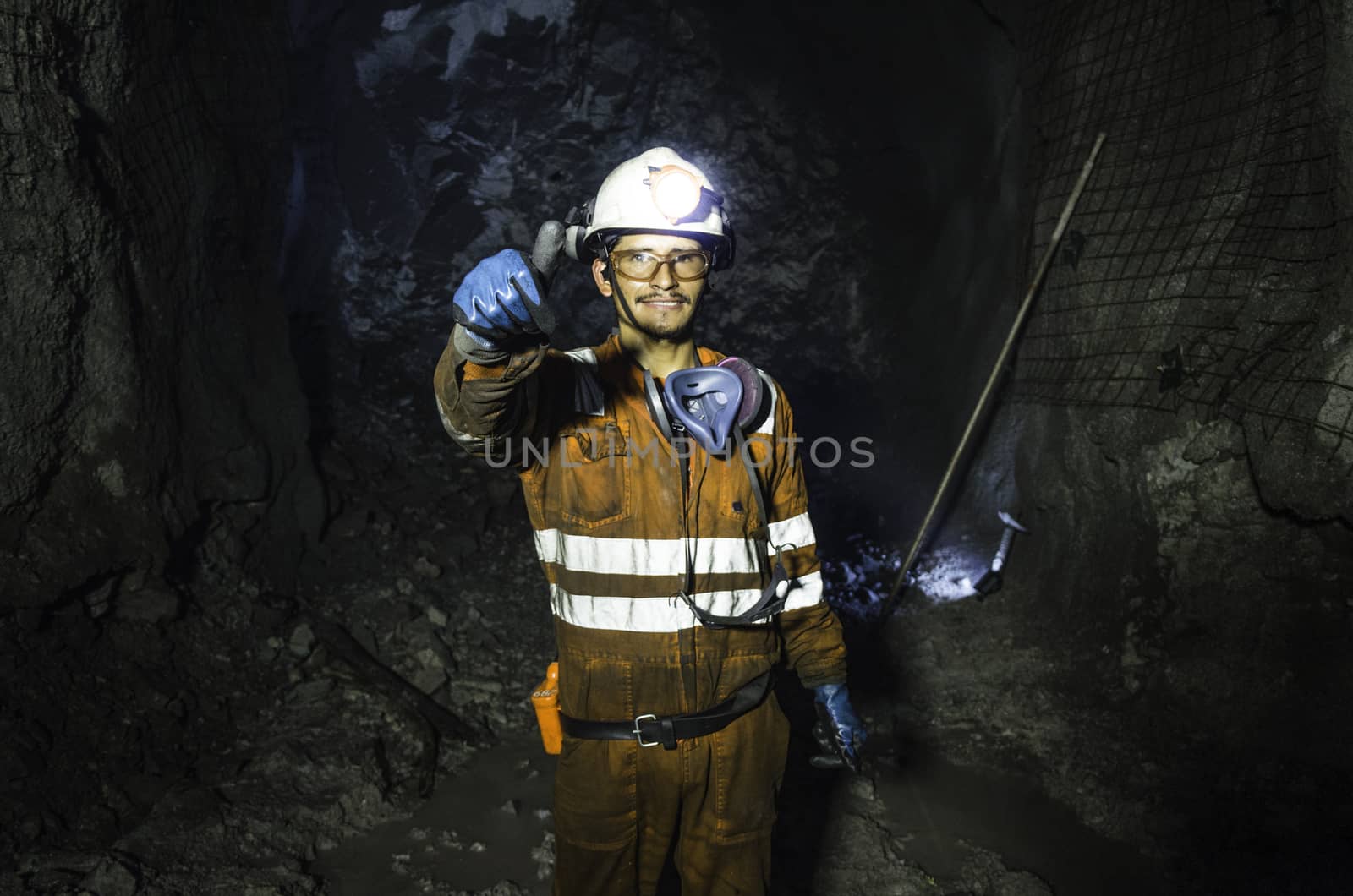 Miner in the mine. Well-uniformed miner inside mine raising thumb, conceptual photo