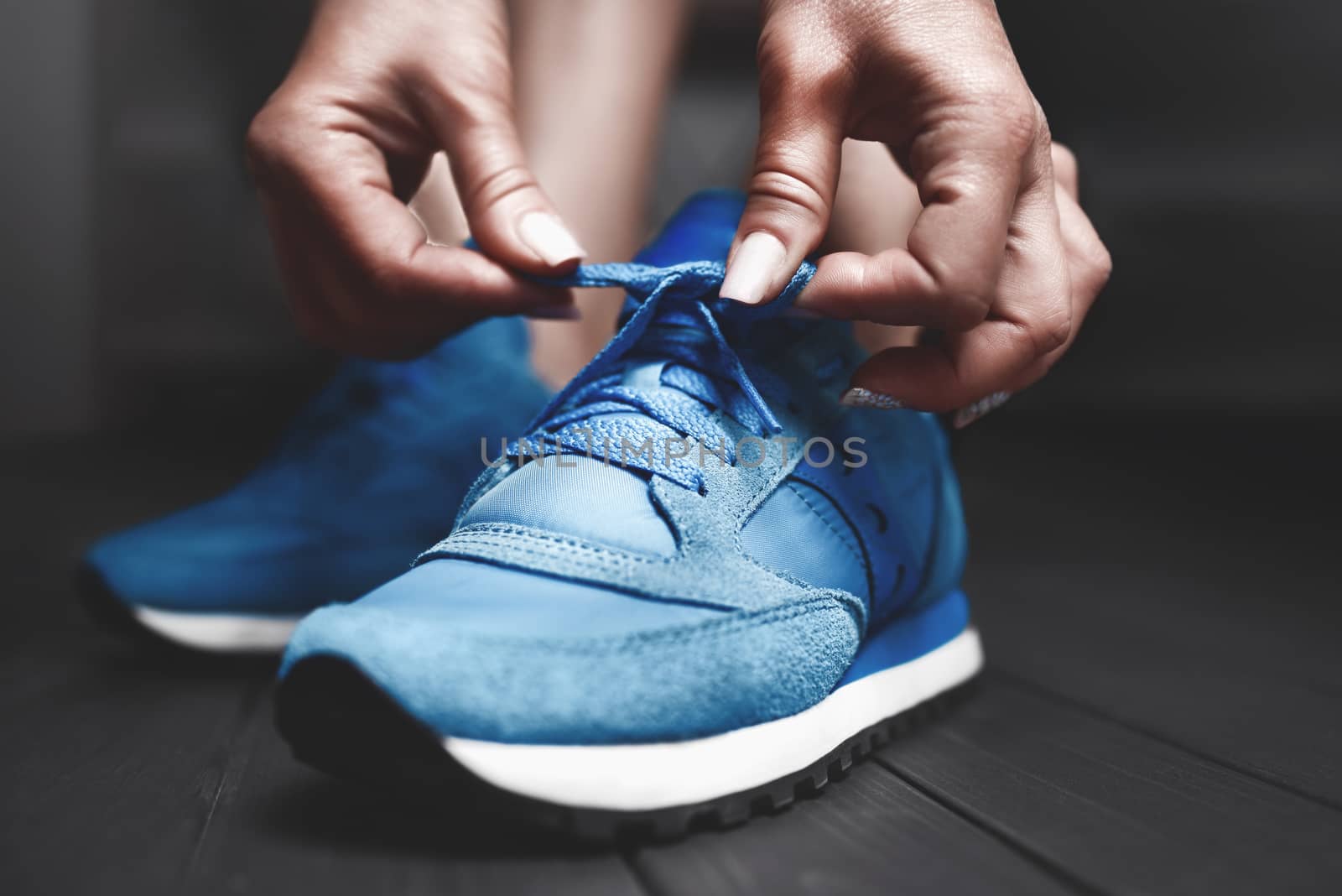 Woman ties up shoelaces on sneakers. Close up view. Healthy lifestyle concept.