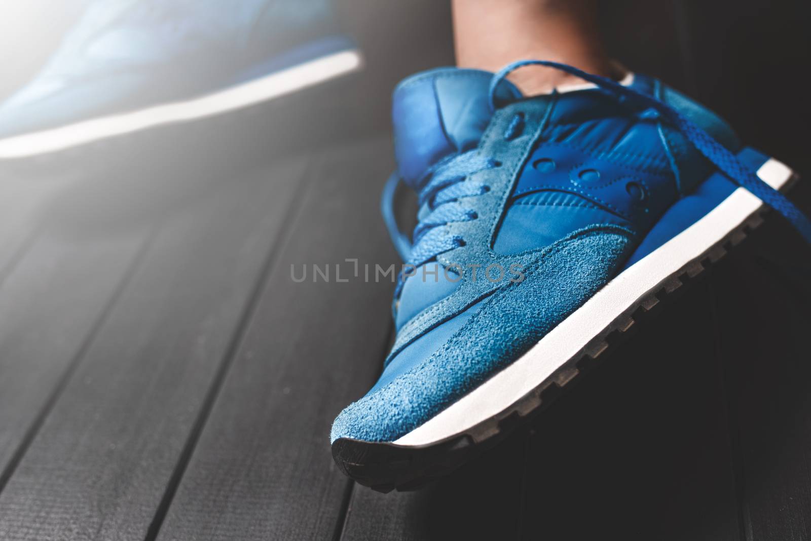 Close up women's legs on wooden background, blue Sneakers ,Women's shoes,spot focus.